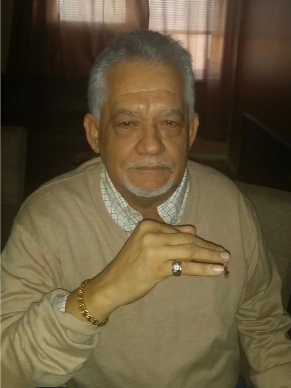 A man sitting on a couch with a ring on his finger.