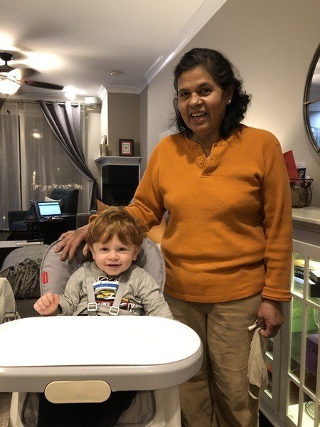 a person standing next to a child in a highchair