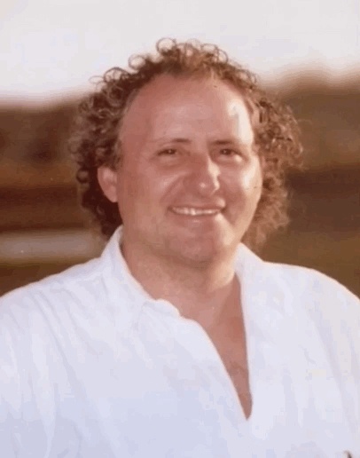 A man in a white shirt with curly hair.