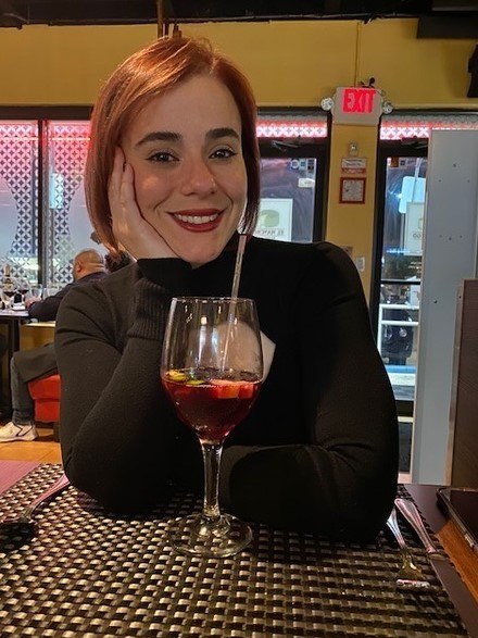 A woman sitting at a bar with a glass of wine.