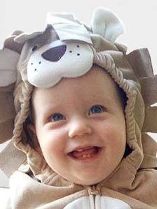 A baby in a lion costume is smiling.