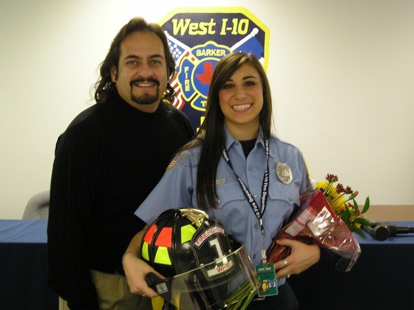 A man and woman standing next to a firefighter's helmet.