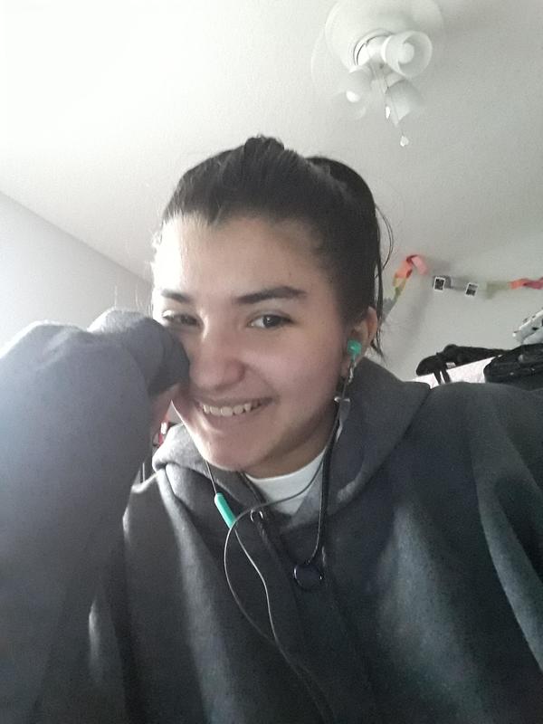 A girl in a gray hoodie with earphones on her head.