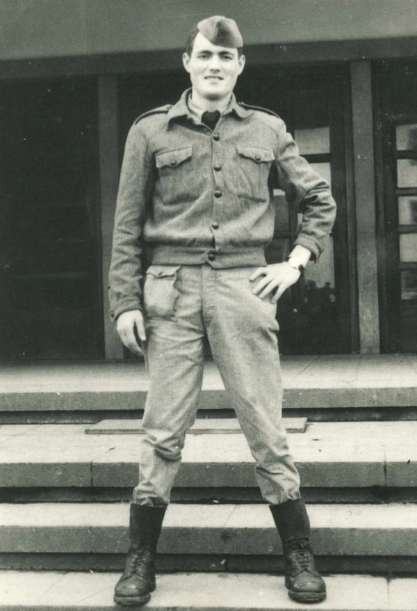 A man in military uniform standing on steps.