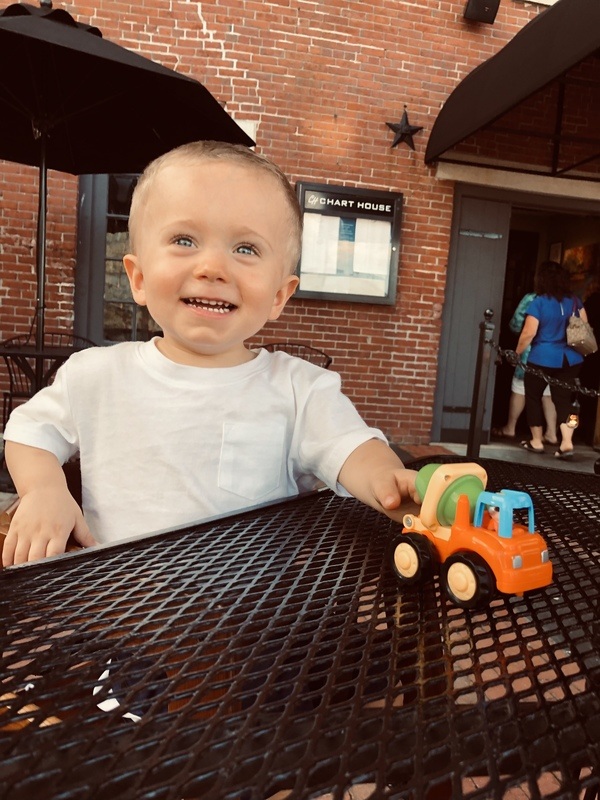 A toddler sitting at a table with a toy truck.