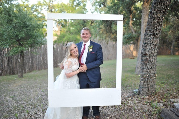 A bride and groom posing in front of a photo frame.