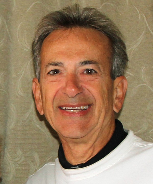 A man in a white shirt smiles for the camera.