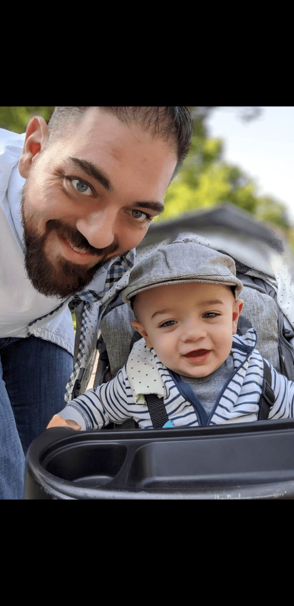 A man is holding a baby in a stroller.