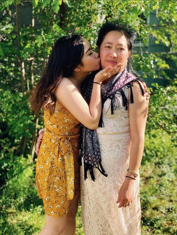 A woman kisses her mother in the park.