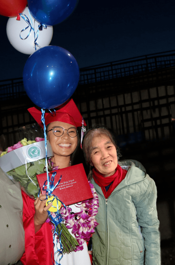 a person in a graduation cap and gown holding a balloon and a gift