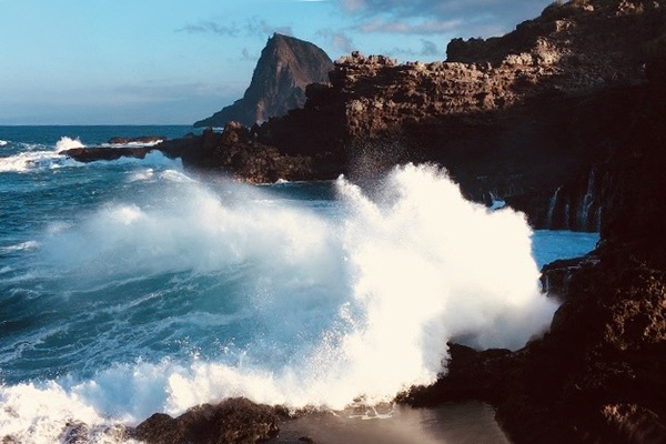 A rocky shore with waves crashing against it.