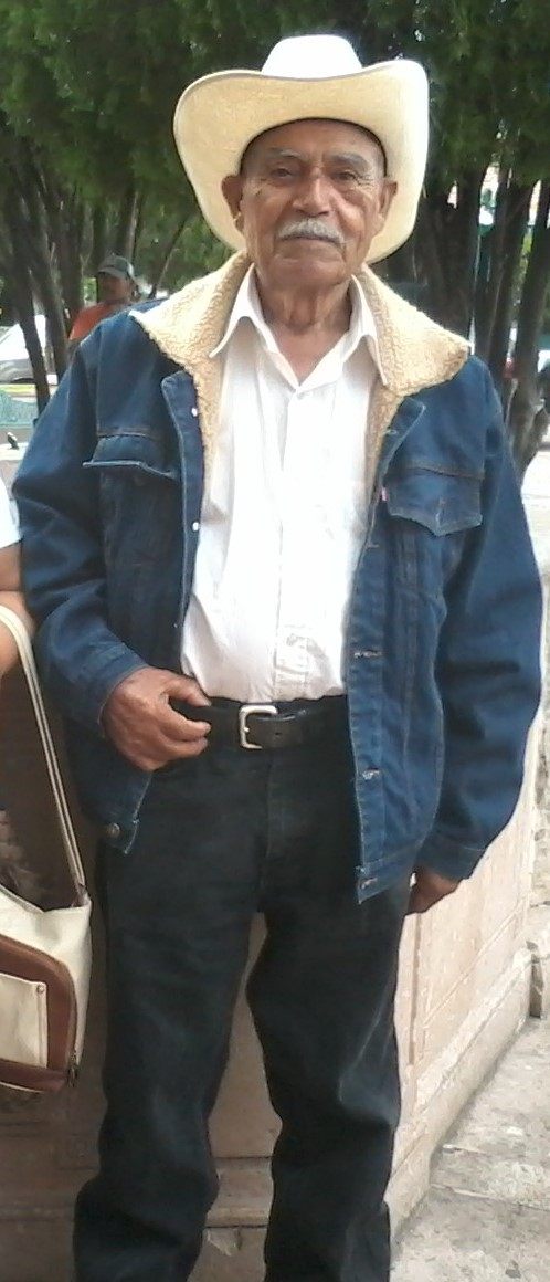 A man in a cowboy hat standing next to a suitcase.