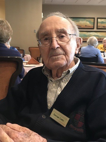 An older man sitting at a table in a restaurant.