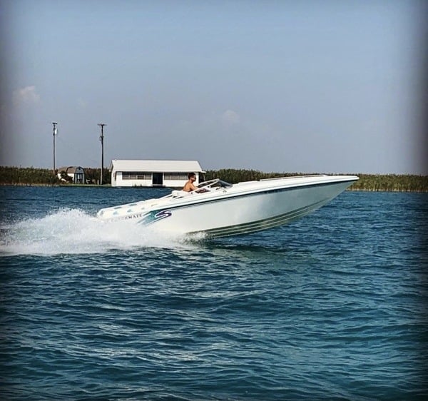 A white speed boat is speeding through the water.