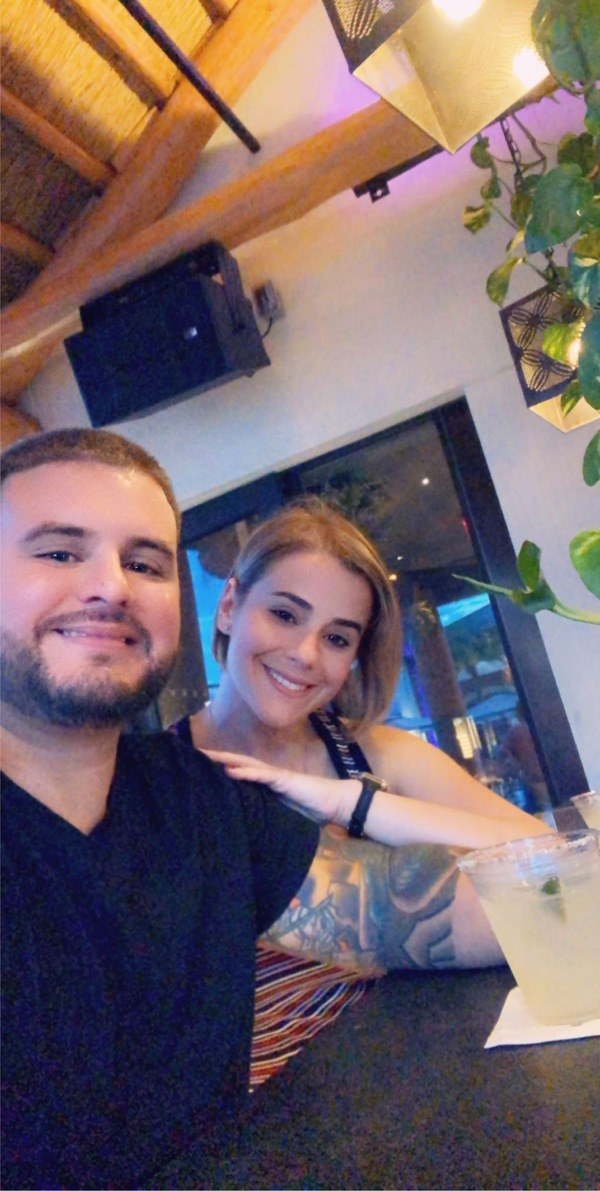 A man and woman posing for a selfie at a bar.
