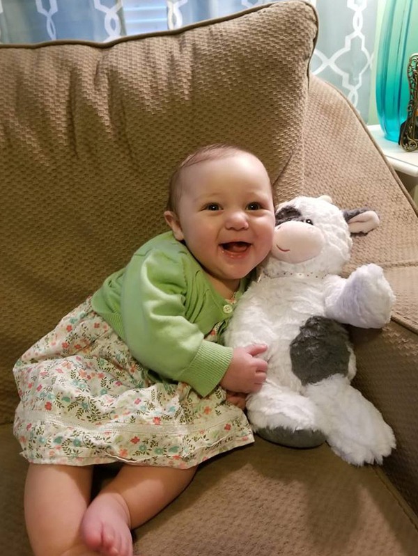 A baby smiles while holding a stuffed animal.
