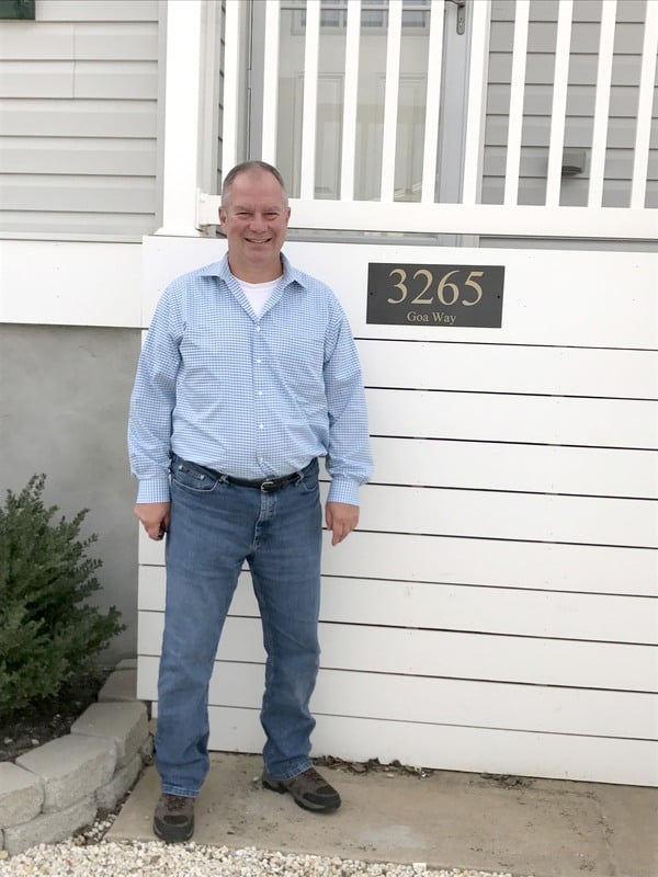 A man standing in front of a house.