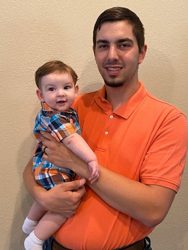 A man holding a baby in an orange shirt.