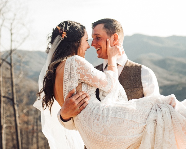 A bride and groom hugging in the mountains.