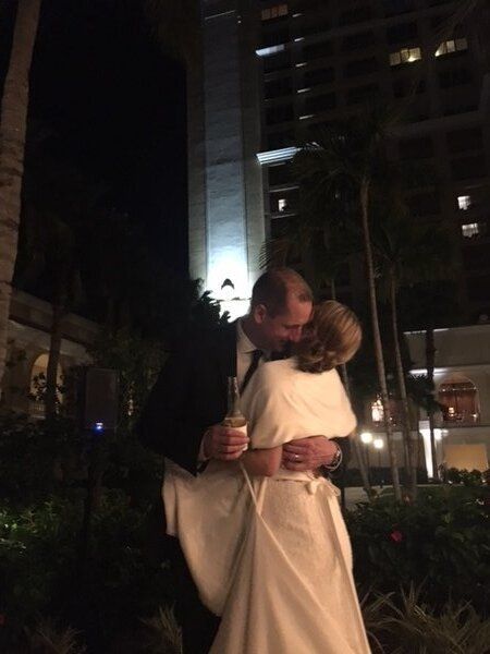 A bride and groom hugging in front of a hotel at night.