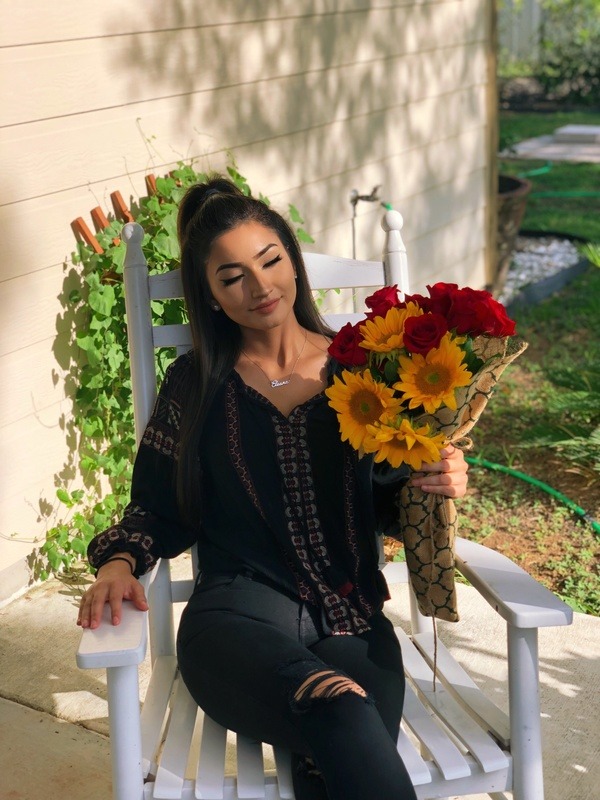 A woman sitting in a rocking chair holding a bouquet of sunflowers.
