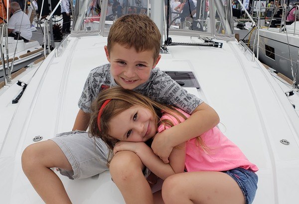 Two children hugging on a sailboat at a boat show.