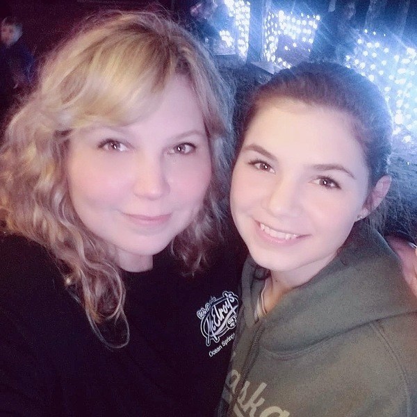 A woman and a girl posing for a selfie at a concert.