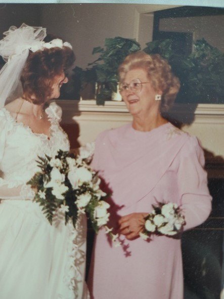 A woman in a pink dress standing next to a woman in a white dress.