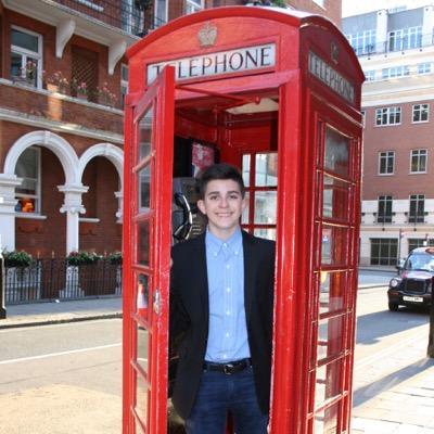 a young boy standing in a red telephone booth
