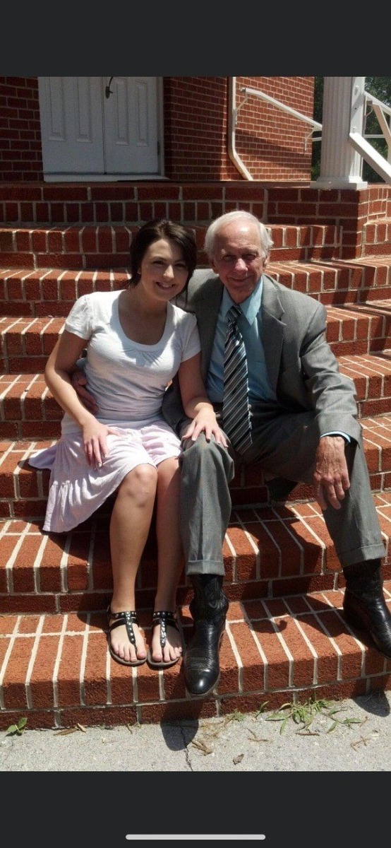 A man and woman sitting on the steps of a brick building.